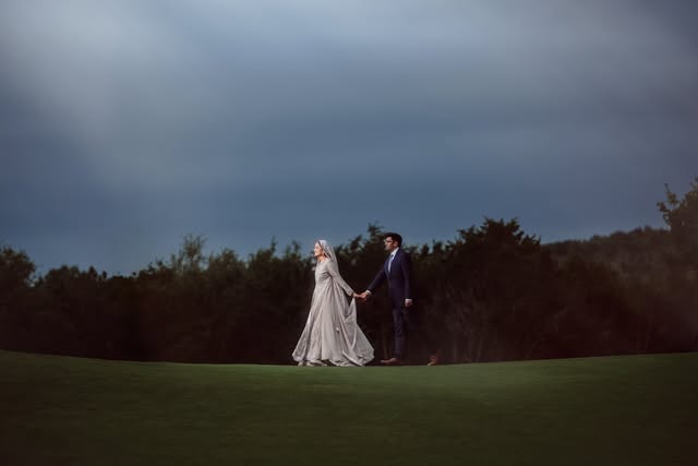 Bride and groom walking a hilltop under a moody sky